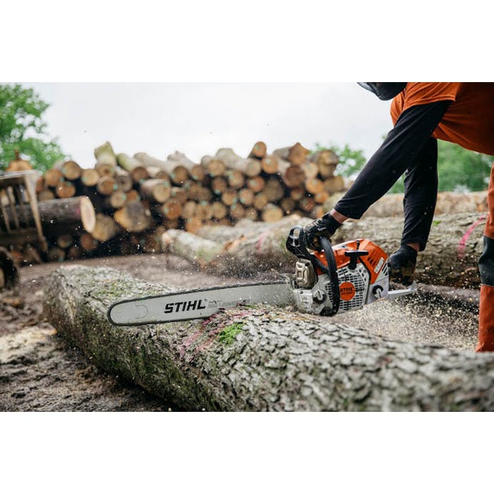 Man cutting log with Stihl chainsaw in lumberyard