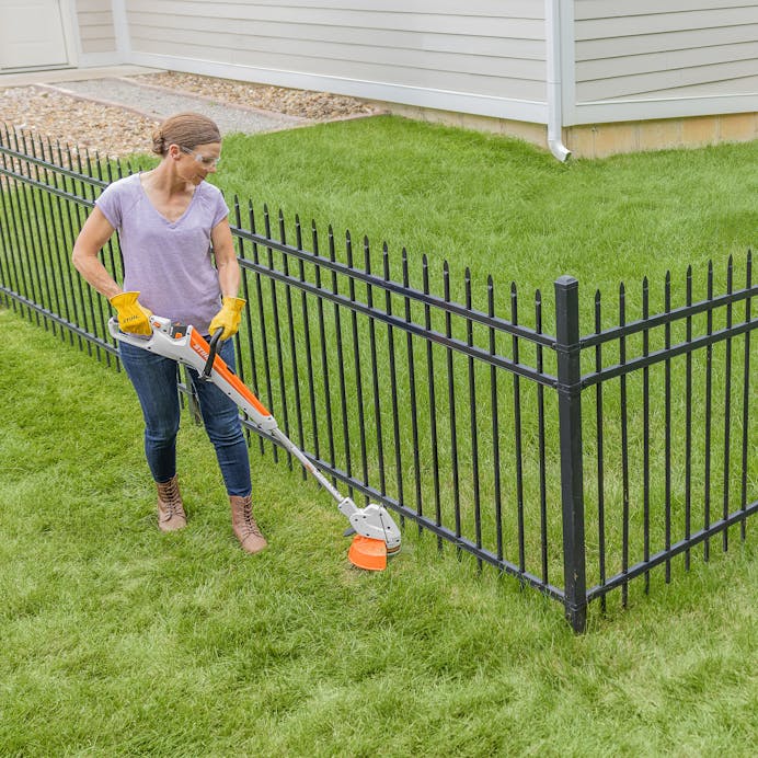 Woman using Stihl Cordless Weed Trimmer in the yard

