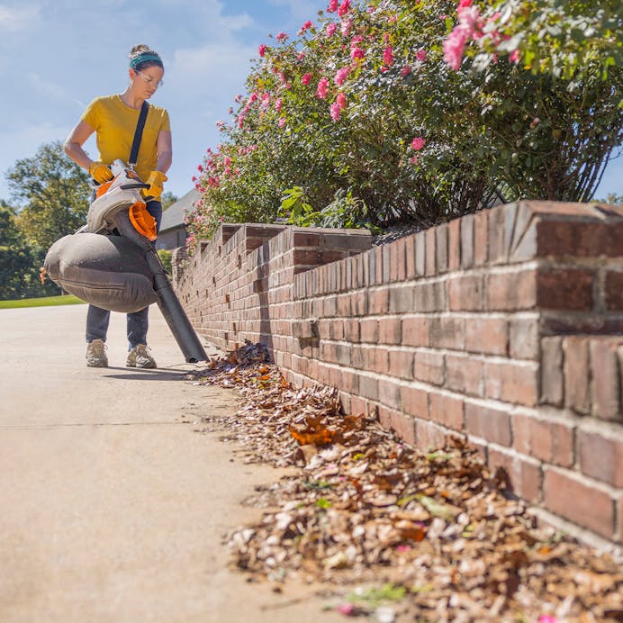 Woman using STIHL® SH 86 C-E on sidewalk