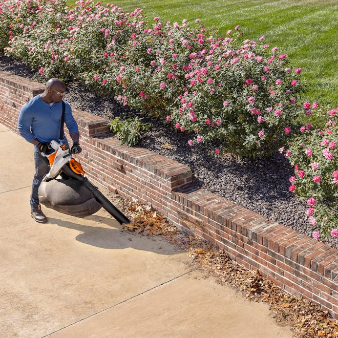 Man using STIHL® SH 86 C-E leaf blower with bag on sidewalk
