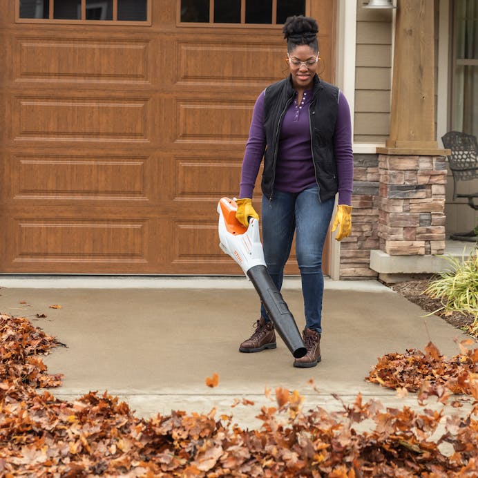Woman using Stihl BGA 60 Cordless Blower in driveway
