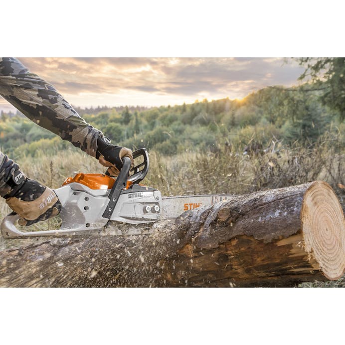 Man in camo long sleeves cutting log with Stihl chainsaw