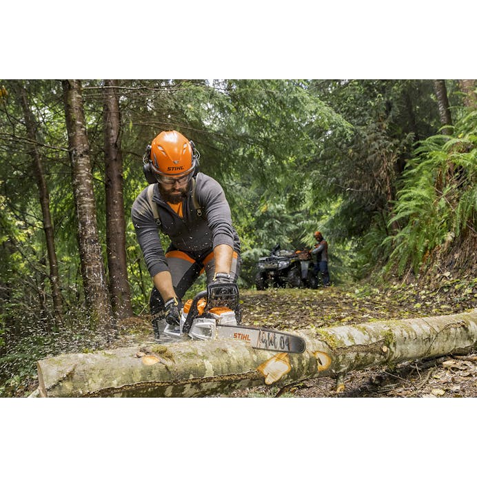 Man cutting log on ground with Stihl chainsaw